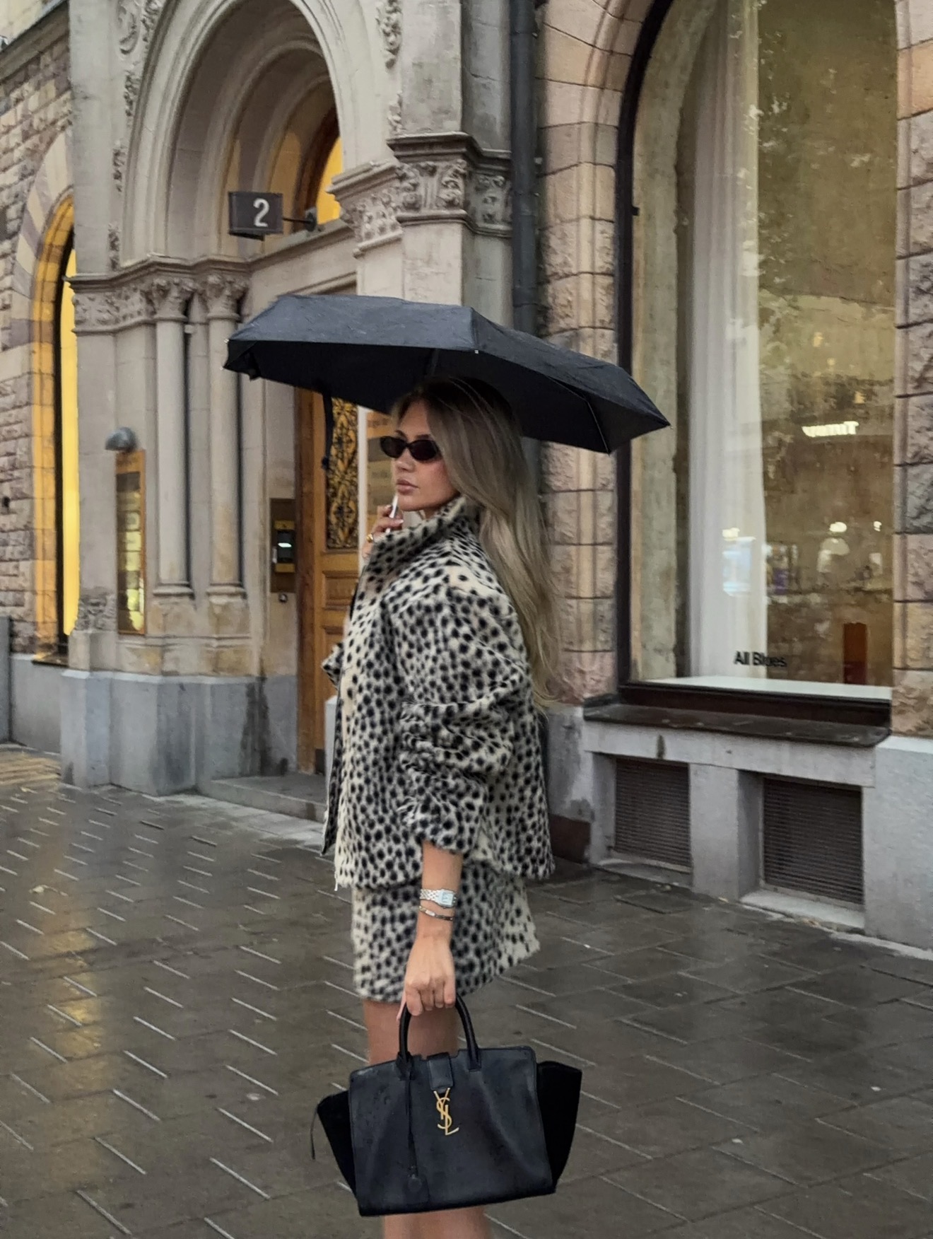 Black Saint Laurent handbag styled with a leopard-print coat