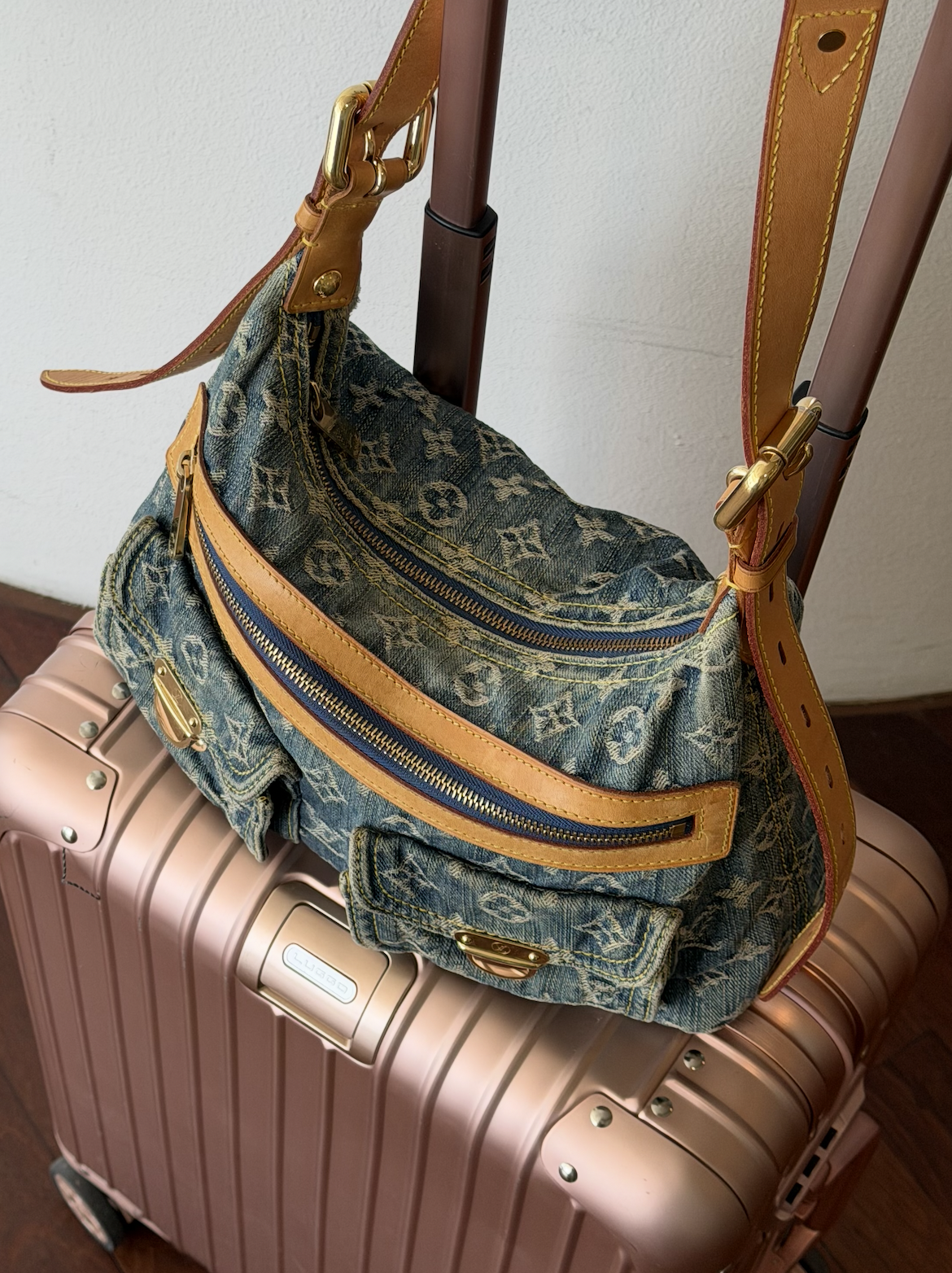 Vintage Louis Vuitton denim bag with leather details resting on a suitcase