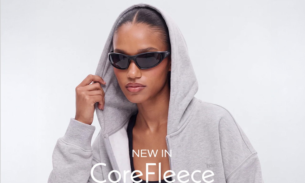 Woman wearing black sunglasses and a grey zip-up hoodie showcasing the new in CoreFleece collection for modern active streetwear fashion.