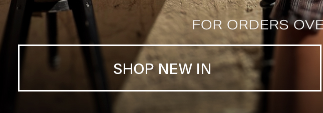 Warm brown studio background with a dark tripod featuring white text reading Shop New In, promoting the latest fashion collection.