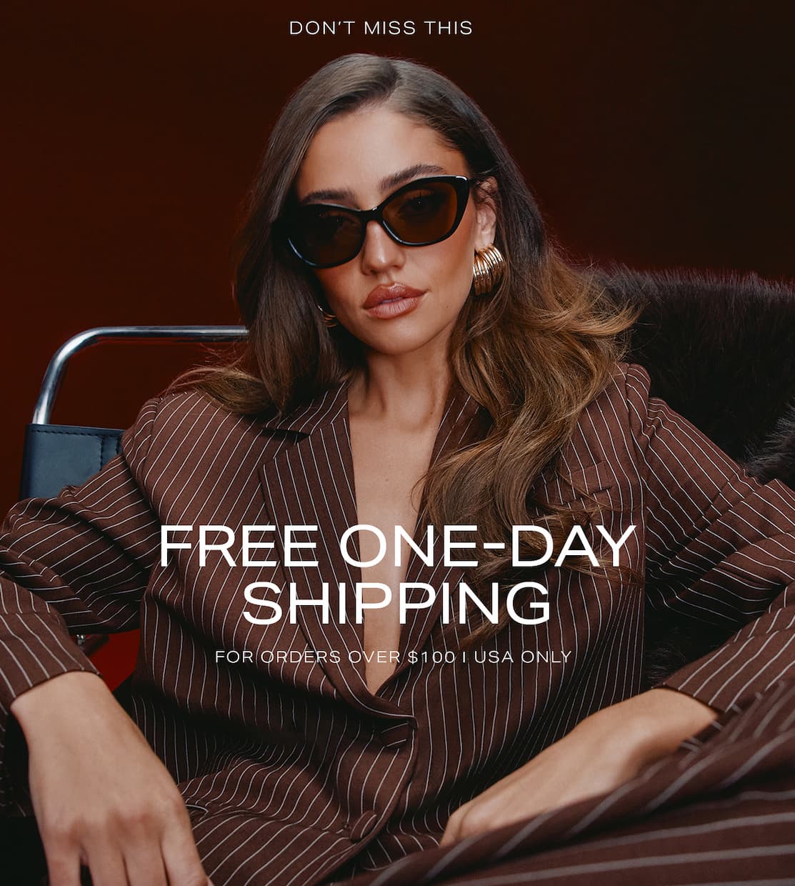 Stylish woman in black sunglasses and a brown pinstripe blazer promoting a free one-day shipping offer for USA orders over $100.